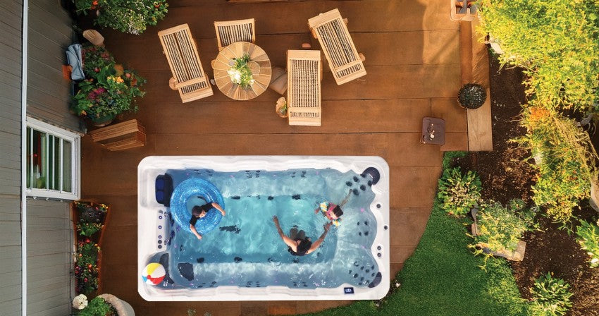 Family gathered around a swim spa on a backyard deck